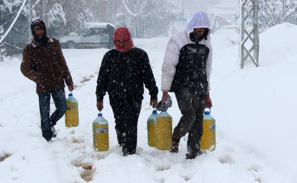 Syrian refugees carry gasoline under heavy snow fall at the a U.N.-run refugee camp of Fayda near the Bekaa Valley town of Zahle in eastern Lebanon on Jan. 7. Syrian refugees carry gasoline under heavy snow fall at the a U.N.-run refugee camp of Fayda near the Bekaa Valley town of Zahle in eastern Lebanon on Jan. 7.