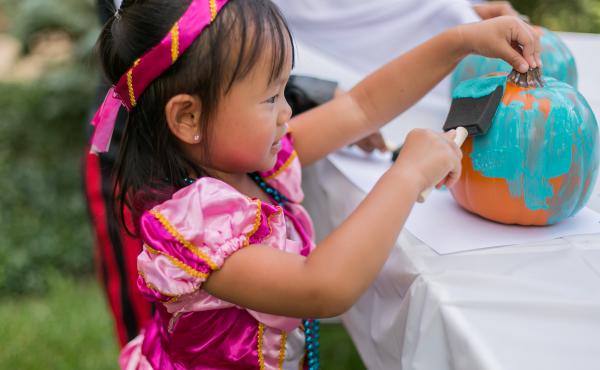 A young girl paints a pumpkin teal to signify that a place is safe for children with food allergies to go trick-or-treating. A young girl paints a pumpkin teal to signify that a place is safe for children with food allergies to go trick-or-treating.