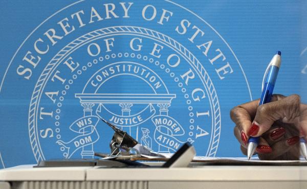 In this Dec. 14, 2020, file photo, a voter fills out paperwork before casting a ballot the first day of early voting for the Senate runoff election in Atlanta. In this Dec. 14, 2020, file photo, a voter fills out paperwork before casting a ballot the first day of early voting for the Senate runoff election in Atlanta.