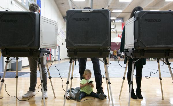 A 2-year-old waits between her father's legs as he and other voters cast their ballots at a polling station set up at Grady High School in Atlanta on Election Day. The state is one of a handful that still use voting machines that don't provide a paper rec A 2-year-old waits between her father's legs as he and other voters cast their ballots at a polling station set up at Grady High School in Atlanta on Election Day. The state is one of a handful that still use voting machines that don't provide a paper rec