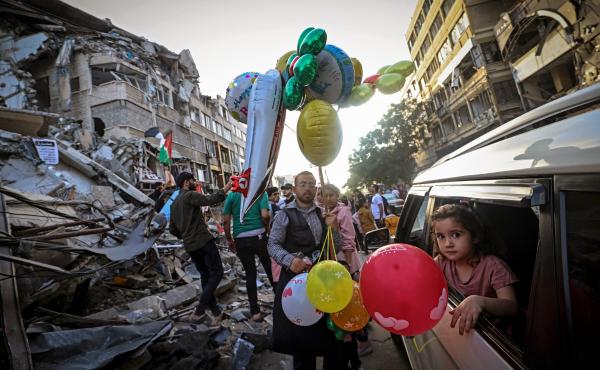 A Palestinian man sells balloons on Friday in Gaza City in front of the Al-Shuruq building, which was destroyed by an Israeli air strike. A Palestinian man sells balloons on Friday in Gaza City in front of the Al-Shuruq building, which was destroyed by an Israeli air strike.