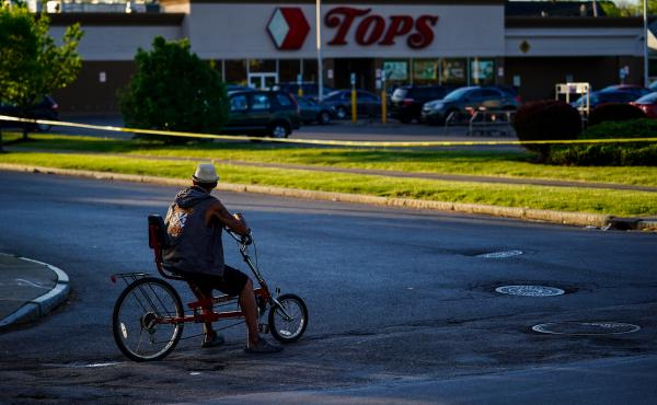 A cyclist pauses outside the site of the supermarket shooting in Buffalo, N.Y. With the Tops store closed for the foreseeable future, the community around it has been left without easy access to healthy and affordable food. A cyclist pauses outside the site of the supermarket shooting in Buffalo, N.Y. With the Tops store closed for the foreseeable future, the community around it has been left without easy access to healthy and affordable food.