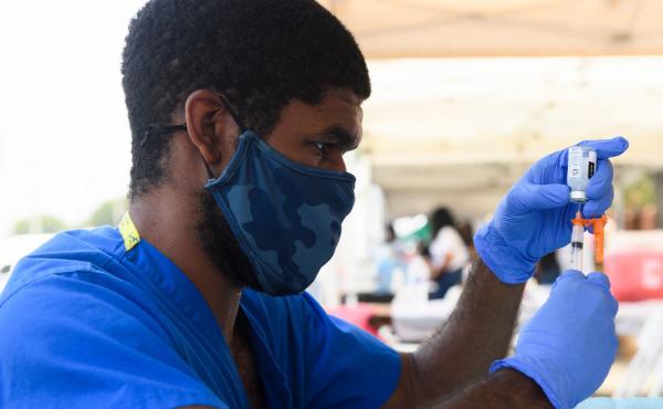 A health care worker prepares a dose of the Moderna COVID-19 vaccine during a clinic held at the Watts Juneteenth Street Fair in the Watts neighborhood of Los Angeles. A health care worker prepares a dose of the Moderna COVID-19 vaccine during a clinic held at the Watts Juneteenth Street Fair in the Watts neighborhood of Los Angeles.