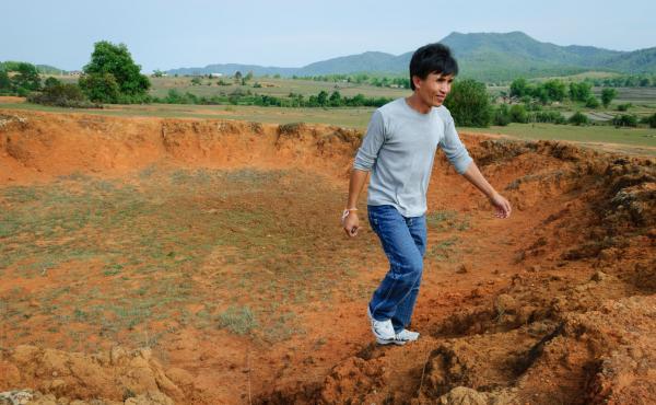 Manophet climbs out of a crater in rural Xieng Khouang, Laos — a remnant of the U.S. bombing campaign during the Vietnam War. Manophet climbs out of a crater in rural Xieng Khouang, Laos — a remnant of the U.S. bombing campaign during the Vietnam War.