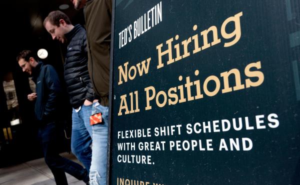 Pedestrians walk past a Now Hiring sign in Arlington, Va., on March 16. Pedestrians walk past a Now Hiring sign in Arlington, Va., on March 16.