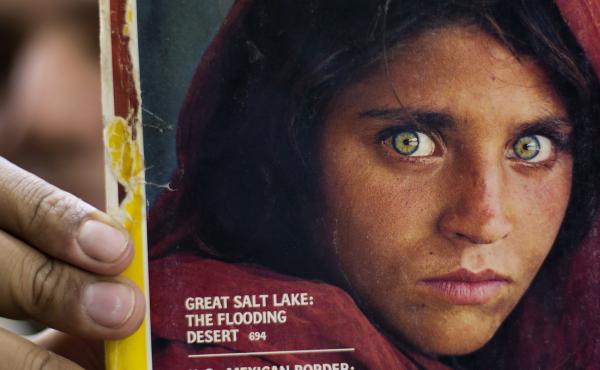 In this file photo from 2016, a bookshop owner in Pakistan shows a National Geographic magazine with the cover photograph of Afghan refugee woman Sharbat Gula. She arrived in Italy as part of the West's evacuation of Afghans following the Taliban takeover In this file photo from 2016, a bookshop owner in Pakistan shows a National Geographic magazine with the cover photograph of Afghan refugee woman Sharbat Gula. She arrived in Italy as part of the West's evacuation of Afghans following the Taliban takeover