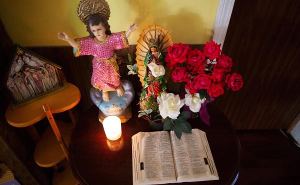 A Bible and other religious symbols sit on a table inside Ms. A.B.'s home. A Bible and other religious symbols sit on a table inside Ms. A.B.'s home.