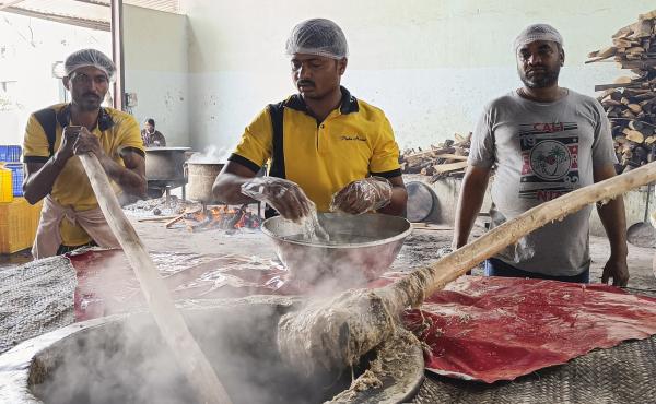 Workers pound the steaming mixture of meat, lentils, wheat and spices with long wooden paddles to give the haleem its signature smooth texture. Workers pound the steaming mixture of meat, lentils, wheat and spices with long wooden paddles to give the haleem its signature smooth texture.