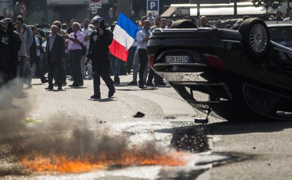 An UberPop vehicle was overturned by French taxi drivers, who also clashed with riot police, during Thursday's protest of the app-based ride-hailing company. An UberPop vehicle was overturned by French taxi drivers, who also clashed with riot police, during Thursday's protest of the app-based ride-hailing company.