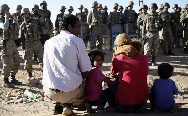 A Syrian family waits near the Turkish-Syrian border after entering Turkey near the town of Sanliurfa Sunday. An estimated 70,000 Syrian Kurds have fled the extremist group the Islamic State this weekend. A Syrian family waits near the Turkish-Syrian border after entering Turkey near the town of Sanliurfa Sunday. An estimated 70,000 Syrian Kurds have fled the extremist group the Islamic State this weekend.
