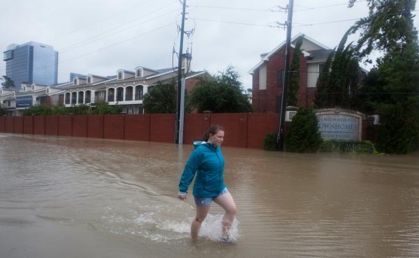 Kelli Walker wasn't able to get into her family's home, on the other side of the brick wall, because of the depth of the rising floodwater in Houston on Tuesday. Kelli Walker wasn't able to get into her family's home, on the other side of the brick wall, because of the depth of the rising floodwater in Houston on Tuesday.