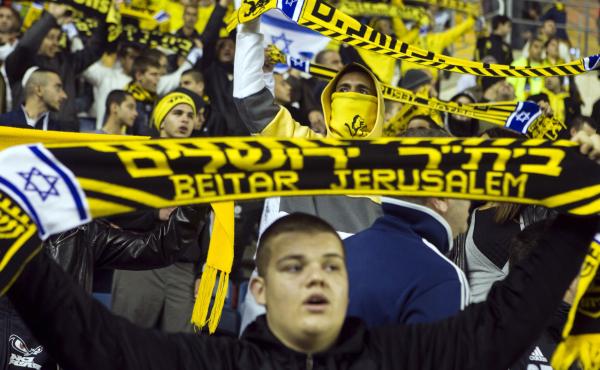 Fans of Beitar Jerusalem, often known as La Familia, hold up scarves during a match against Bnei Sakhnin at Teddy Stadium in Jerusalem. With a reputation for aggression and racist behavior, La Familia has come under the scrutiny of city leaders. Fans of Beitar Jerusalem, often known as La Familia, hold up scarves during a match against Bnei Sakhnin at Teddy Stadium in Jerusalem. With a reputation for aggression and racist behavior, La Familia has come under the scrutiny of city leaders.