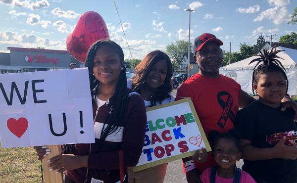 LeCandice Durham, Lenny Lane and their children stand by the Tops parking lot entrance in Buffalo, N.Y., on Friday to welcome back customers and employees on opening day after the supermarket was closed after May's mass shooting. LeCandice Durham, Lenny Lane and their children stand by the Tops parking lot entrance in Buffalo, N.Y., on Friday to welcome back customers and employees on opening day after the supermarket was closed after May's mass shooting.