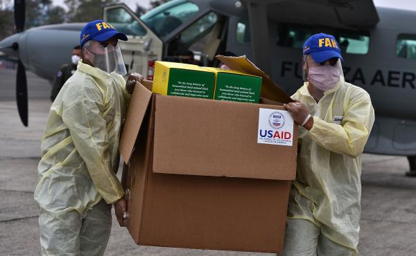 Foreign aid takes many forms — and Trump and Biden have differing perspectives. Above: Members of the Honduran Armed Forces carry a box of COVID-19 diagnostic testing kits donated by the United States Agency for International Development and the Interna Foreign aid takes many forms — and Trump and Biden have differing perspectives. Above: Members of the Honduran Armed Forces carry a box of COVID-19 diagnostic testing kits donated by the United States Agency for International Development and the Interna