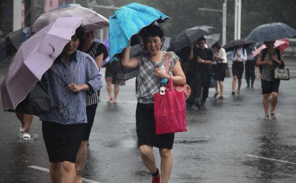 Pedestrians shield themselves from wind and rain brought by Typhoon Lingling Saturday, in Pyongyang, North Korea. Pedestrians shield themselves from wind and rain brought by Typhoon Lingling Saturday, in Pyongyang, North Korea.