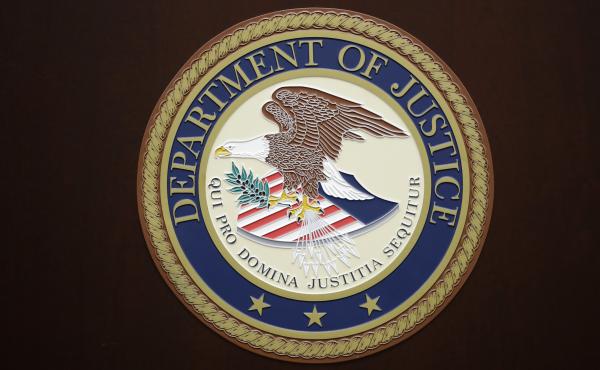 The U.S. Department of Justice logo is seen on a podium in Baltimore, last year. The U.S. Department of Justice logo is seen on a podium in Baltimore, last year.