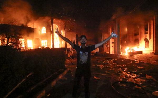 An Iraqi protester stands flashing the victory gesture outside the burning headquarters of the Iranian Consulate in Basra on Sept. 7. An Iraqi protester stands flashing the victory gesture outside the burning headquarters of the Iranian Consulate in Basra on Sept. 7.