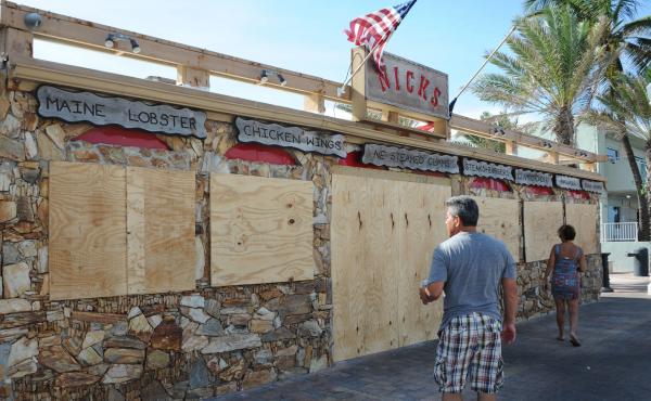 Tourists walk past a restaurant, closed in preparation for hurricane Irma, in Fort Lauderdale, Fla., on Sept. 7. The Bureau of Labor Statistics says a drop in U.S. jobs in September was likely reflecting the impact of hurricanes on workers — particularl Tourists walk past a restaurant, closed in preparation for hurricane Irma, in Fort Lauderdale, Fla., on Sept. 7. The Bureau of Labor Statistics says a drop in U.S. jobs in September was likely reflecting the impact of hurricanes on workers — particularl