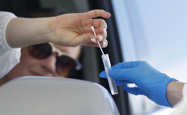 A woman drops a nasal swab in a vial at the announcement that Denver will launch a drive-up COVID-19 test site. A woman drops a nasal swab in a vial at the announcement that Denver will launch a drive-up COVID-19 test site.