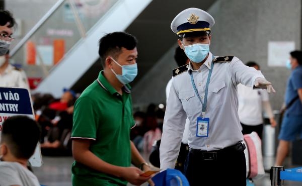 A staff member from Vietnam's disease control authority assists passengers as they queue up for temperature checks at the departure terminal at Da Nang's international airport on Monday. A staff member from Vietnam's disease control authority assists passengers as they queue up for temperature checks at the departure terminal at Da Nang's international airport on Monday.