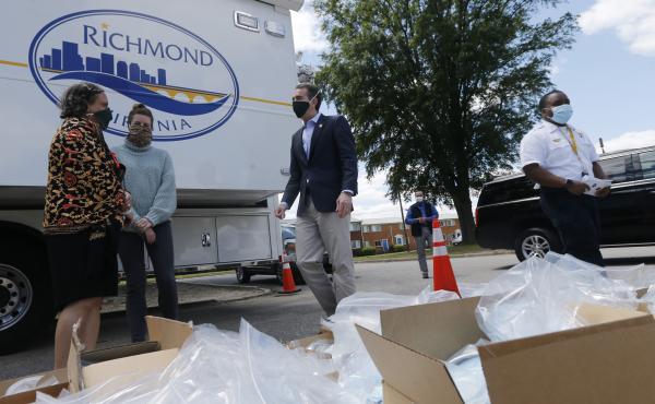 Virginia Gov. Ralph Northam (center) walks past boxes of personal protective equipment that volunteers plan to distribute Tuesday at an event in Richmond. Northam is doing a phased reopening in parts of the state outside the Washington, D.C., suburbs. Virginia Gov. Ralph Northam (center) walks past boxes of personal protective equipment that volunteers plan to distribute Tuesday at an event in Richmond. Northam is doing a phased reopening in parts of the state outside the Washington, D.C., suburbs.