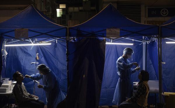 Health workers administer COVID tests outside a building placed under lockdown in Hong Kong on Jan. 6. Hong Kong is imposing strict new COVID measures for the first time in almost a year as the omicron variant seeps into the community. Health workers administer COVID tests outside a building placed under lockdown in Hong Kong on Jan. 6. Hong Kong is imposing strict new COVID measures for the first time in almost a year as the omicron variant seeps into the community.