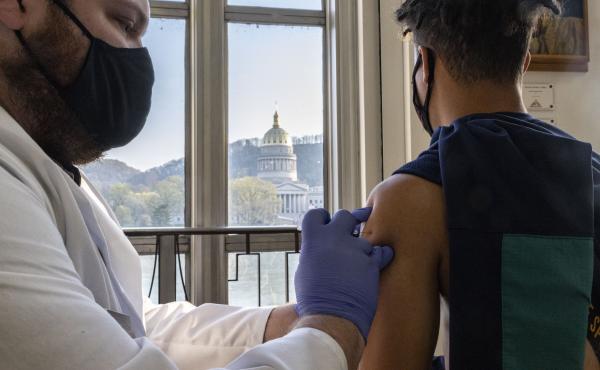 A young man receives a COVID-19 vaccine in Charleston earlier this month while overlooking the West Virginia Capitol building. A young man receives a COVID-19 vaccine in Charleston earlier this month while overlooking the West Virginia Capitol building.