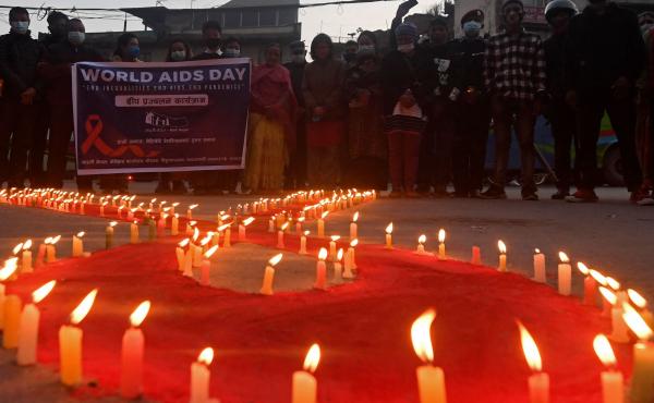 Volunteers stand after lighting candles in the shape of a red ribbon during an awareness event ahead of World AIDS Day in Kathmandu on Tuesday. Volunteers stand after lighting candles in the shape of a red ribbon during an awareness event ahead of World AIDS Day in Kathmandu on Tuesday.