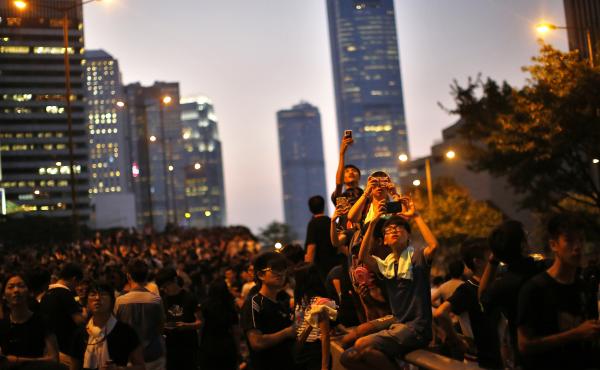 Protesters take pictures with their mobile phones on Monday as they block the main street to the financial Central district, outside the government headquarters in Hong Kong. Protesters take pictures with their mobile phones on Monday as they block the main street to the financial Central district, outside the government headquarters in Hong Kong.