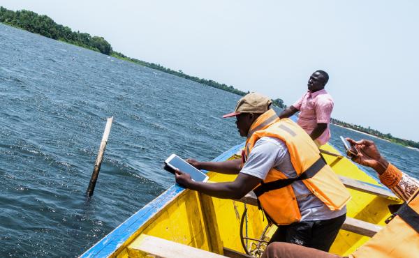 Samuel-Richard Bogobley holds a GPS-enabled tablet to capture the location of one corner of an underwater clam "farm" belonging to Kofi Amatey, in pink, in Ghana's Volta River estuary. Samuel-Richard Bogobley holds a GPS-enabled tablet to capture the location of one corner of an underwater clam "farm" belonging to Kofi Amatey, in pink, in Ghana's Volta River estuary.