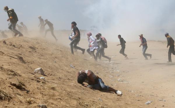 Palestinian demonstrators run or take cover from tear gas fired by Israeli forces at the Israel-Gaza border. Palestinian demonstrators run or take cover from tear gas fired by Israeli forces at the Israel-Gaza border.