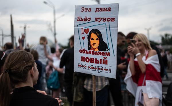 Anti-government protesters hold a sign with a picture depicting Belarusian opposition leader Svetlana Tikhanovskaya as a card that trumps an ace on Aug. 23 in Minsk. Anti-government protesters hold a sign with a picture depicting Belarusian opposition leader Svetlana Tikhanovskaya as a card that trumps an ace on Aug. 23 in Minsk.