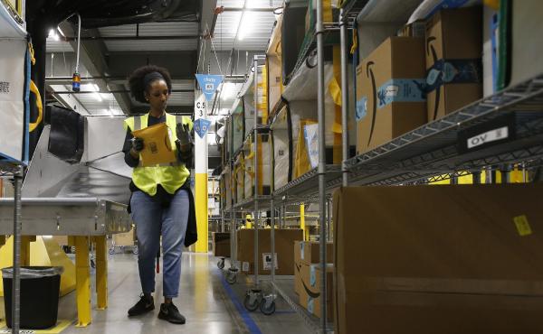 An Amazon worker stows packages into special containers at a facility in Arizona. Coronavirus cases have been reported in at least 7 Amazon facilities. An Amazon worker stows packages into special containers at a facility in Arizona. Coronavirus cases have been reported in at least 7 Amazon facilities.