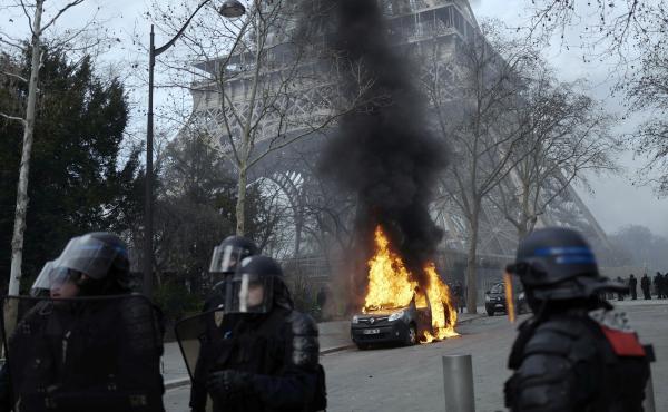 A burning command car belonging to France's anti-terror squad is pictured as riot police take position near the Eiffel Tower. A burning command car belonging to France's anti-terror squad is pictured as riot police take position near the Eiffel Tower.