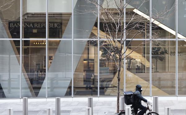 A delivery person rides a bicycle past a storefront in New York City. A delivery person rides a bicycle past a storefront in New York City.