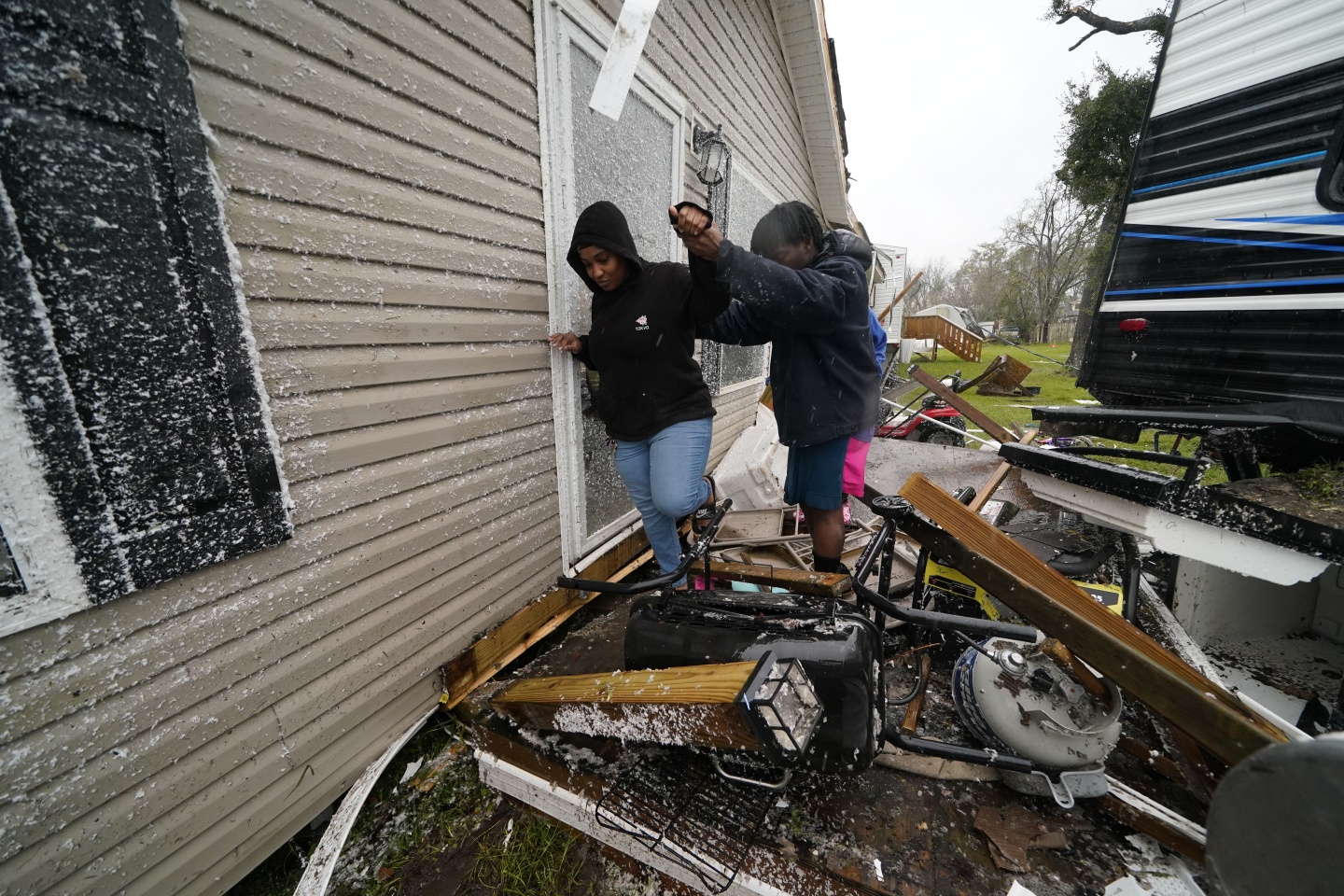 People help each other through the rubble after a tornado tore through the area in Killona, La., about 30 miles west of New Orleans in St. James Parish, Wednesday, Dec. 14, 2022.