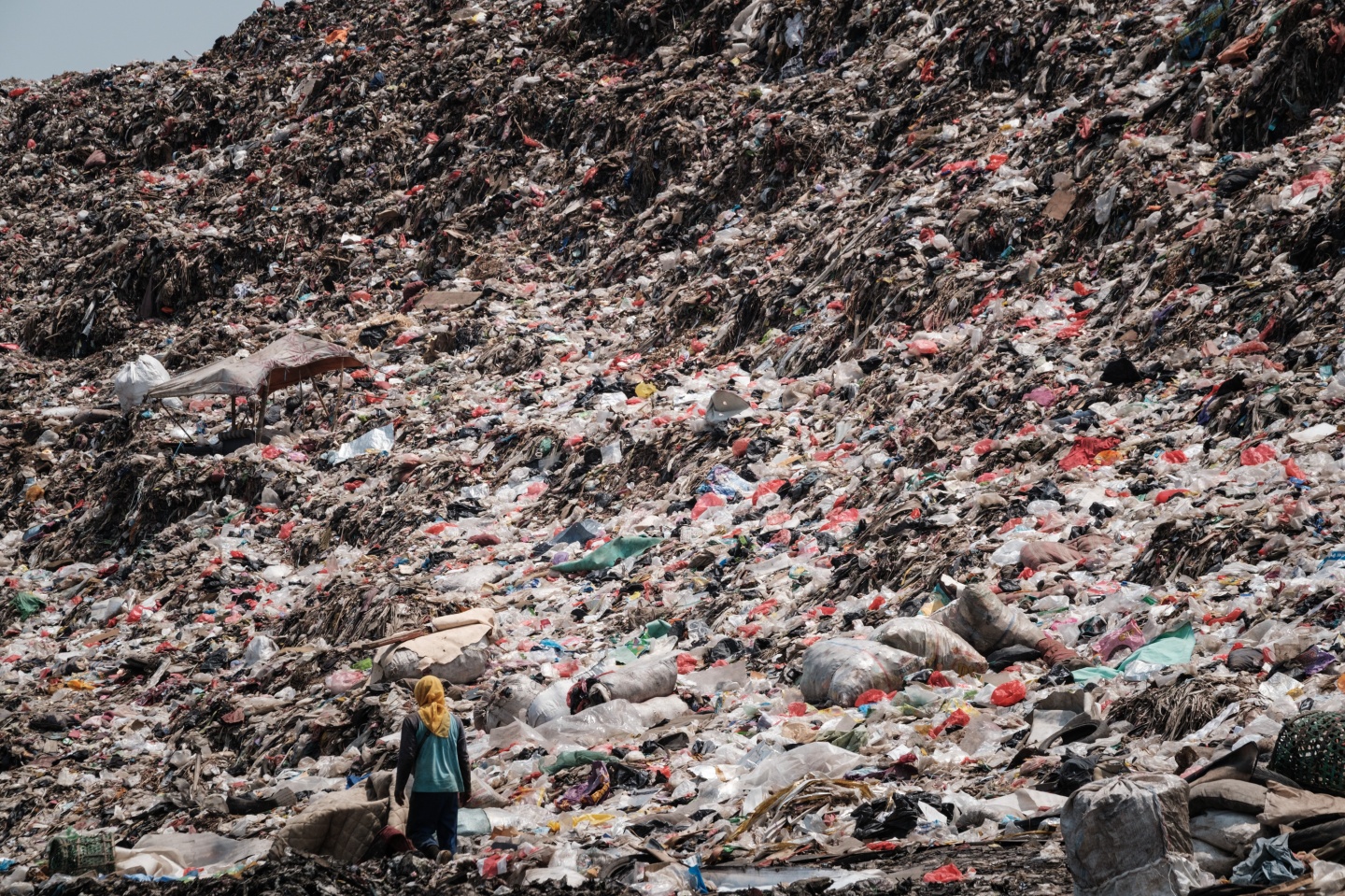 A registered scavenger, who mainly collects plastic waste to sell, walking in a landfill in Indonesia.